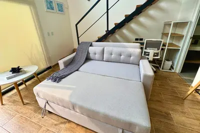 a couch in a living room with a staircase at Tiny House con Piscina Privada, Jacuzzi, Parrilla y Starlink in Punta Negra