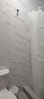 a white bathroom with a toilet and a shower at Hostal Pulpos in Bombiso