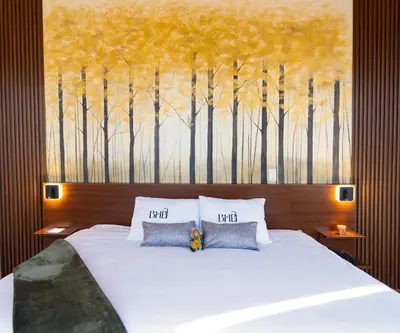 a bedroom with a bed and a painting of trees at Bosco Hotel Boutique in Cusco