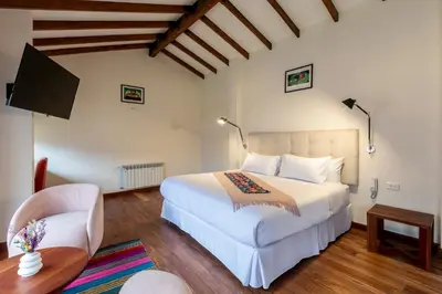 a bedroom with a large white bed and a chair at Casa Eva Hotel Boutique in Urubamba