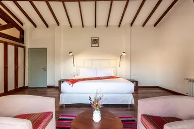 a bedroom with a bed and two chairs and a table at Casa Eva Hotel Boutique in Urubamba