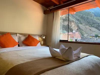 a bedroom with a bed with a large window at Juliet's House in Ollantaytambo