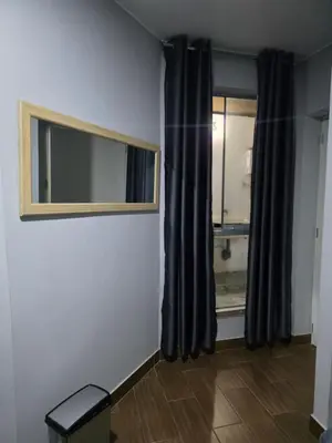 a room with a window with black curtains and a mirror at Aero- apartamento in Lima
