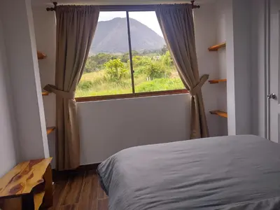 a bedroom with a large window with a mountain view at Sweet Home Oxapampa in Oxapampa
