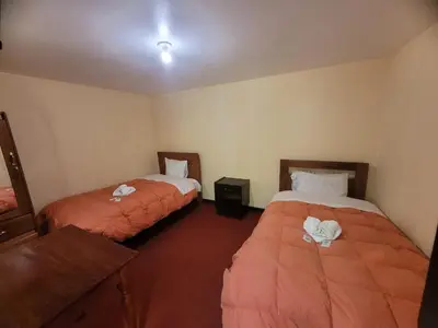 a room with two beds in a room at HOTEL HUAYNAPATA Pardo in Cusco