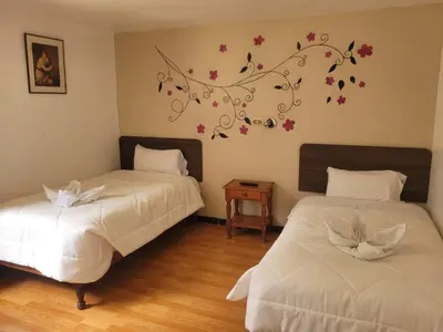 a bedroom with two beds with flowers on the wall at HOTEL HUAYNAPATA Pardo in Cusco