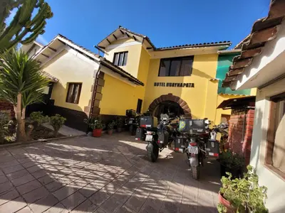 two motorcycles parked in front of a yellow building at HOTEL HUAYNAPATA Pardo in Cusco