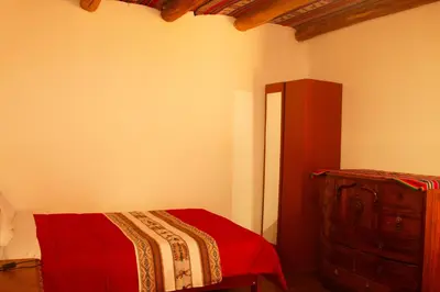 a bedroom with a bed and a dresser at Hospedaje Pumayalli in Urubamba