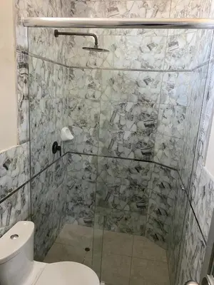 a bathroom with a glass shower with a toilet at Mablia Suite in Ica