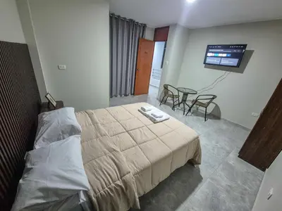 a bedroom with a bed and a table and a television at Mablia Suite in Ica