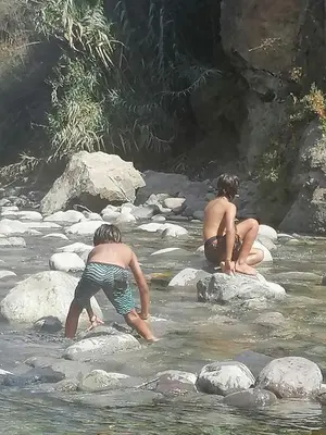 two boys are playing in the water on rocks at Tornameza Casa de Campo in Torna Mesa