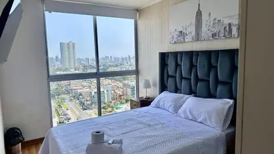a bedroom with a bed with a large window at Apartment in front of the Ricardo Palma Clinic in Lima