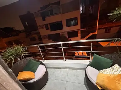 a balcony with two chairs with pillows on it at Departamento Palmeras in Lima