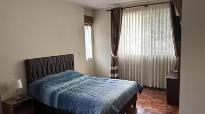 a bedroom with a bed with a blue comforter and a window at Departamento centrico cusco in Cusco
