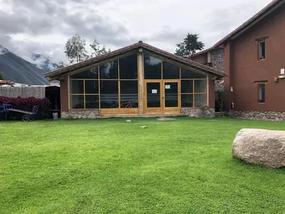a house with a large glass window on a yard at Lizzy Wasi Urubamba in Urubamba