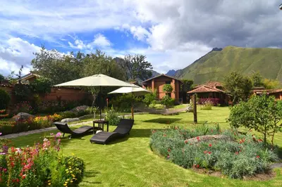 a garden with a table and chairs and an umbrella at Lizzy Wasi Urubamba in Urubamba