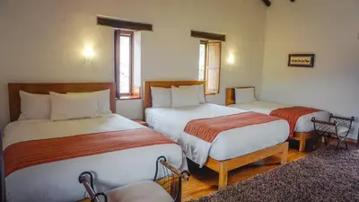a bedroom with two beds and two chairs at Lizzy Wasi Urubamba in Urubamba