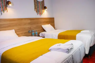 a room with two beds with yellow and white at Hotel Litan Machu Picchu in Machu Picchu