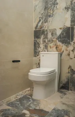 a white toilet in a bathroom with marble tiles at Luxurious Apt with Rooftop, BBQ, and Beach nearby in Punta Hermosa