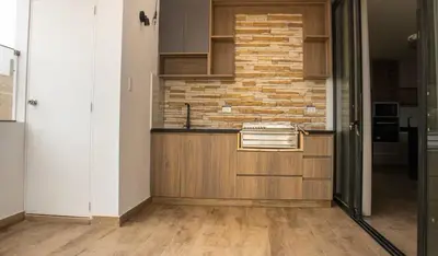a kitchen with wooden cabinets and a brick wall at Luxurious Apt with Rooftop, BBQ, and Beach nearby in Punta Hermosa