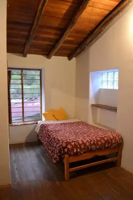 a bedroom with a bed and two windows at Cabaña rodeada de naturaleza en Ollantaytambo in Ollantaytambo