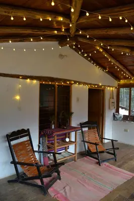two chairs and a table on a patio with lights at Cabaña rodeada de naturaleza en Ollantaytambo in Ollantaytambo