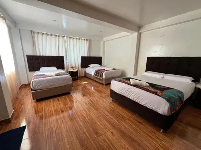 two beds in a room with wooden floors at Tikary Lodge in Cusco
