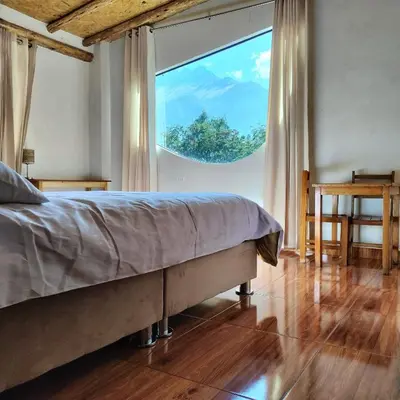 a bedroom with a bed and a large window at Tikary Lodge in Cusco