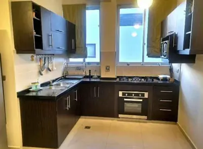 a kitchen with black cabinets and a sink and a window at chaski apart in Cusco