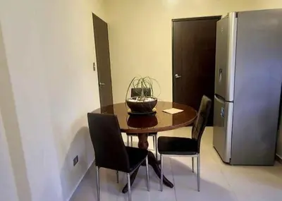 a dining room table with chairs and a refrigerator at chaski apart in Cusco