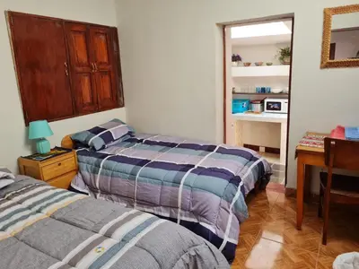 a bedroom with two beds and a desk and a table at Mini departamento 2 camas en el centro in Cusco