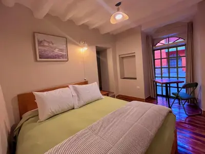 a bedroom with a bed and a table and a window at Casa Terra Cusco in Cusco