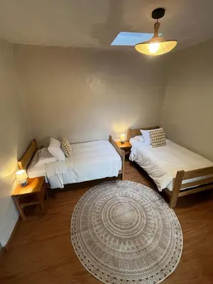 a room with two beds and a rug at Casa Terra Cusco in Cusco