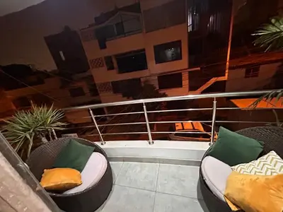 a balcony with two chairs with pillows on it at Departamento Palmeras in Lima