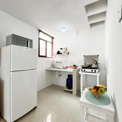 a kitchen with a white refrigerator and a table with a bowl of fruit at Direct Beach Access Apt & Speedy WiFi in Punta Hermosa