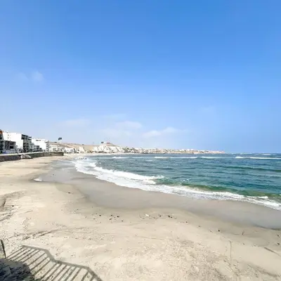 a sandy beach with the ocean and buildings in the background at Direct Beach Access Apt & Speedy WiFi in Punta Hermosa