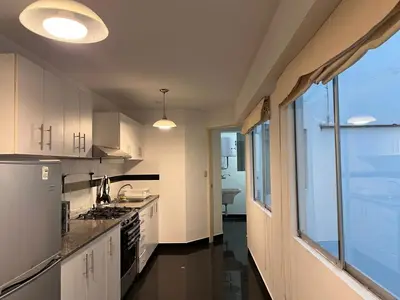 a kitchen with white cabinets and a large window at Villaflores Apartments in Lima