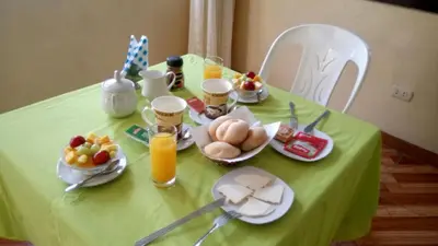 a green table with breakfast foods and drinks on it at Hostal Geminis in Ica