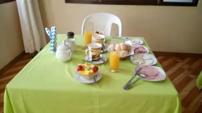 a table with a green table cloth with food and orange juice at Hostal Geminis in Ica