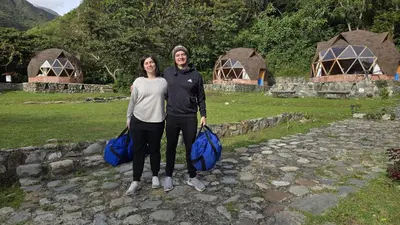 a man and a woman standing on a stone path with luggage at Salkantay Majestic Domes Eco Lodge in Sahuayacu