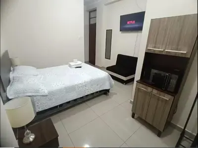 a bedroom with a bed and a tv and a chair at Habitación privada cerca a la plaza Constitución en un 1er piso in Huancayo