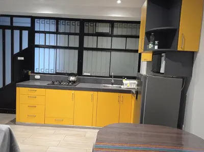a kitchen with yellow cabinets and a stainless steel refrigerator at La Casa de Justi in Huancayo