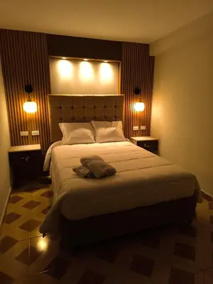 a bedroom with a large bed with two lights on it at Suites Tintaya in Cusco