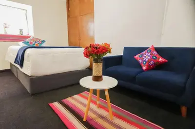 a living room with a couch and a table with flowers at CHARMING AND QUIET apart IN CUSCO in Cusco