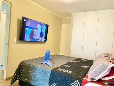 a bedroom with a bed and a tv on the wall at Departamento exclusivo con vista a la ciudad in Lima