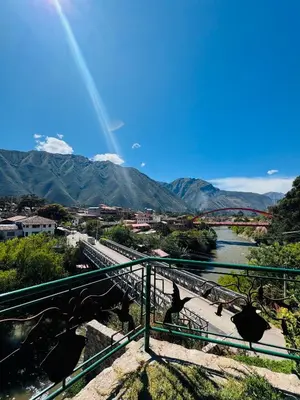 a bridge over a river with a rainbow in the background at Yoga Home in Urubamba