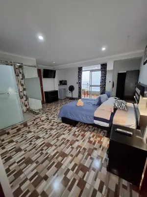a bedroom with a large bed with a wooden floor at Hostal los Faroles in Barranca