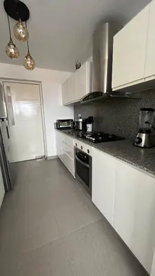 a kitchen with white cabinets and a stove top oven at A 15 minutos del aeropuerto cómodo y moderno departamento de 3 habitaciones independientes y 2 baños in Lima