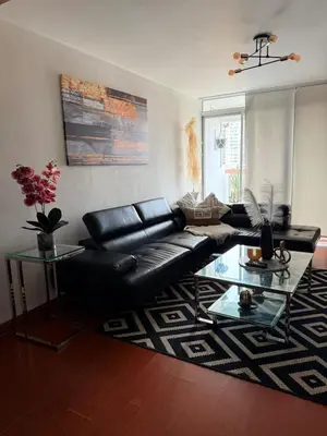 a living room with a black leather couch and a glass table at A 15 minutos del aeropuerto cómodo y moderno departamento de 3 habitaciones independientes y 2 baños in Lima