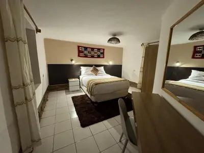 a bedroom with a bed and a table and a mirror at Urquillos Wasi - Andean Cottage in Urubamba